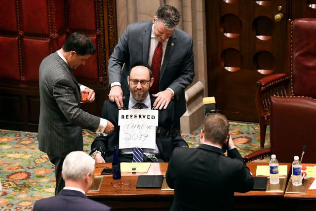 Sen. George Amedore Jr., R-Rotterdam, left, and Sen. Terrence Murphy, R-Carmel, right, tape Sen. Simcha Felder, D-Brooklyn to his chair as a joke while waiting for the start of a session in the Senate Chamber at the state Capitol during the last scheduled day of the legislative session, in Albany